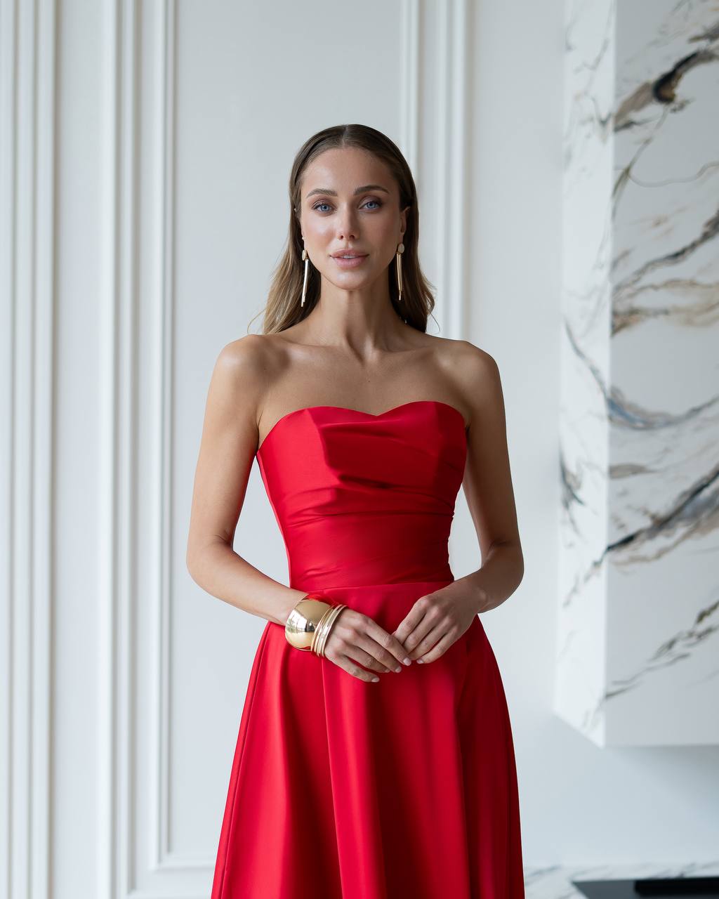 Woman wearing a red strapless dress in an elegant interior setting