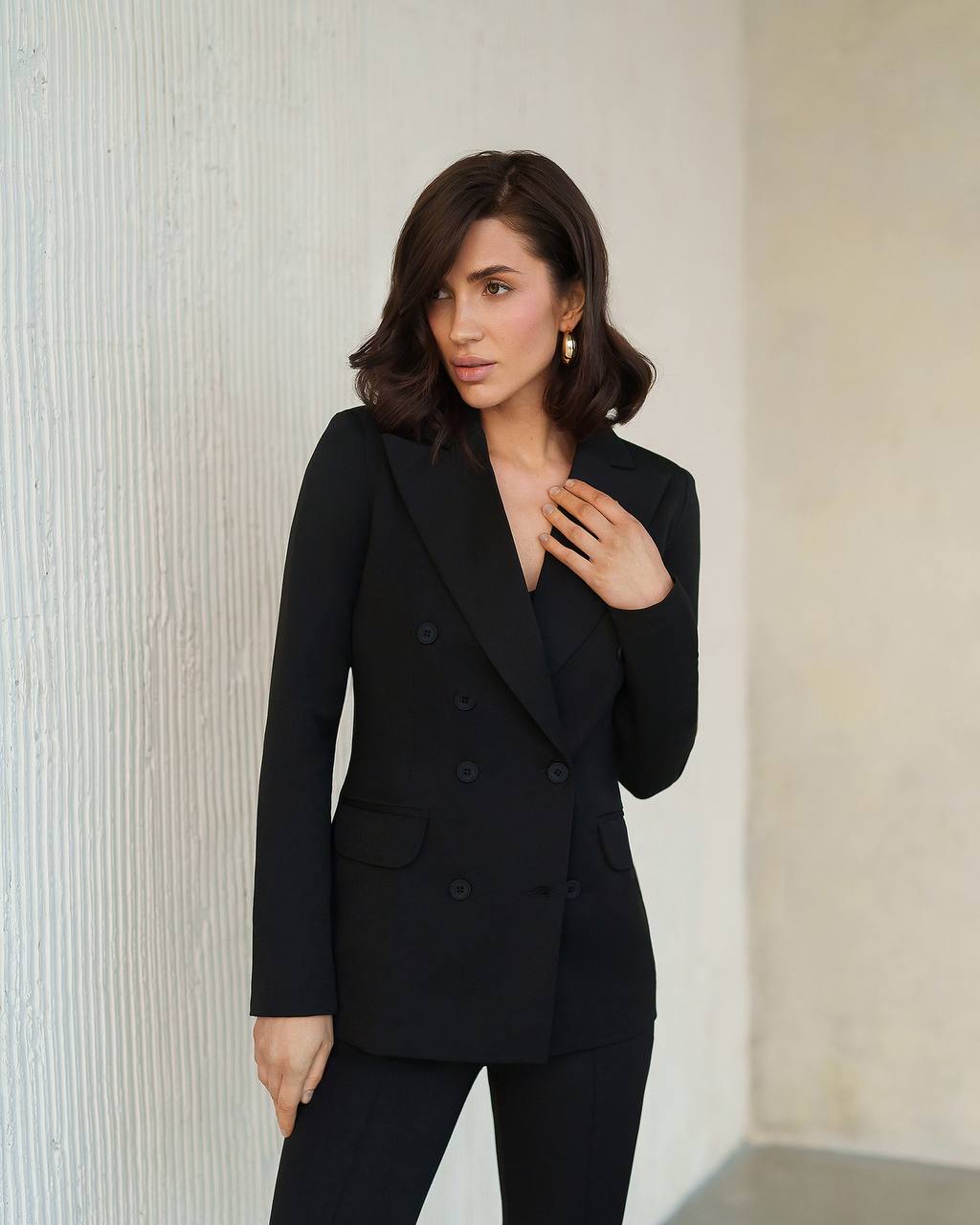 Woman wearing a black suit against a neutral background