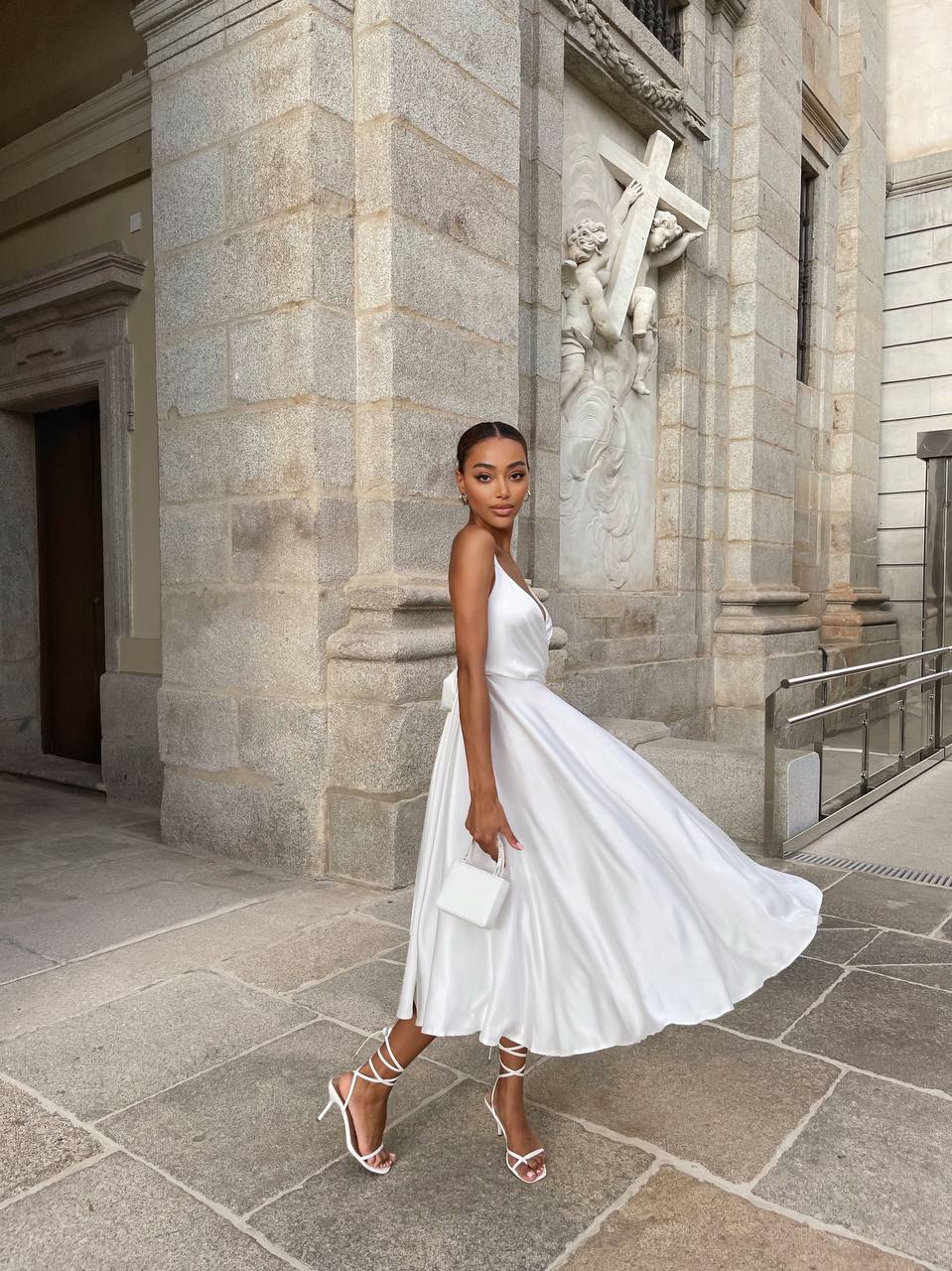 Woman in a white dress standing in front of a stone building