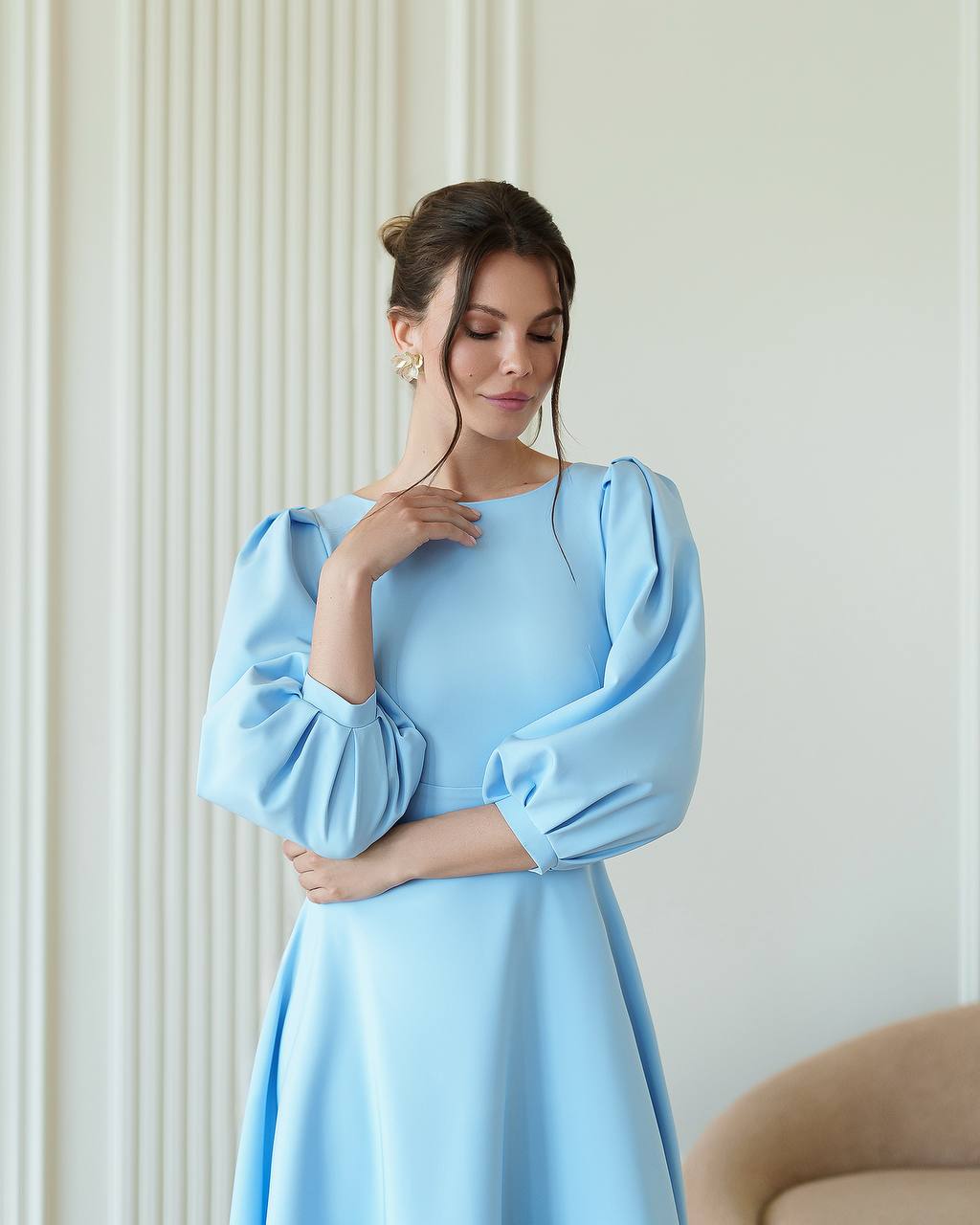 Woman wearing a light blue dress with puffed sleeves in an indoor setting.