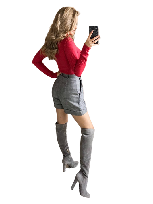 Woman wearing a red top and gray knee-high boots taking a selfie.