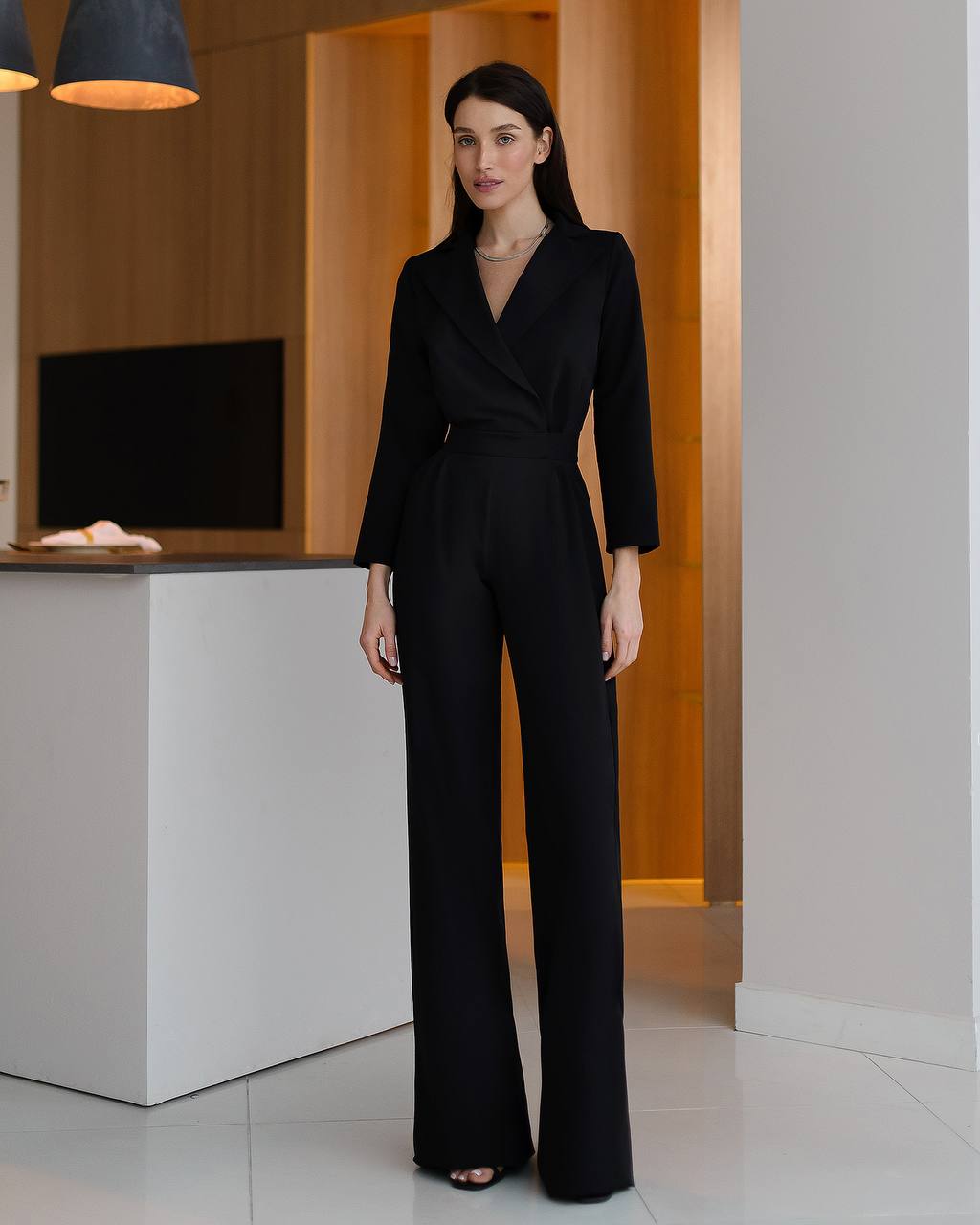 Woman wearing a black jumpsuit in an indoor setting