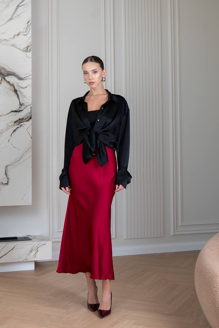 Woman wearing a black top and red skirt in an elegant room.