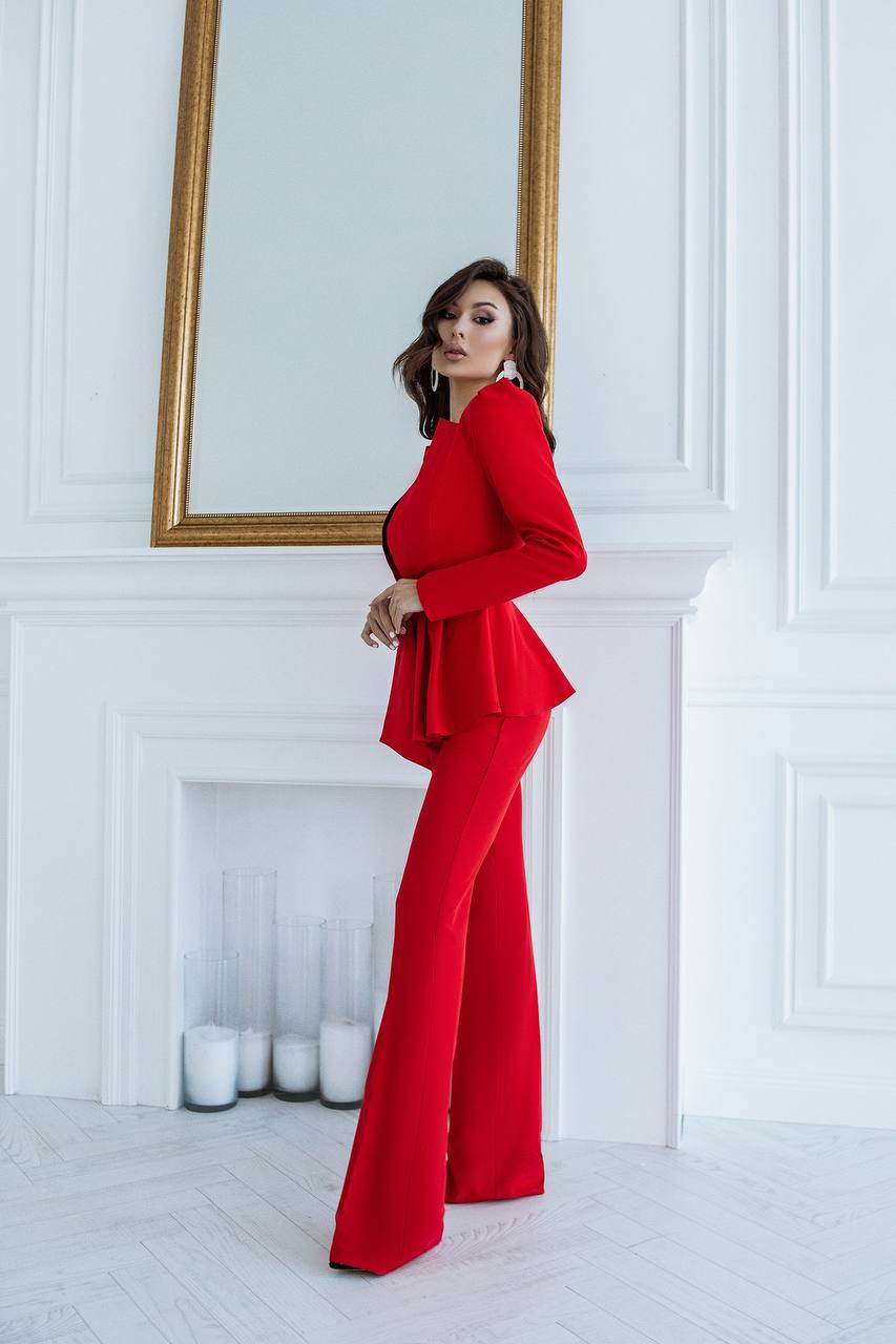 Woman in a red outfit standing in a room with white walls and a fireplace.