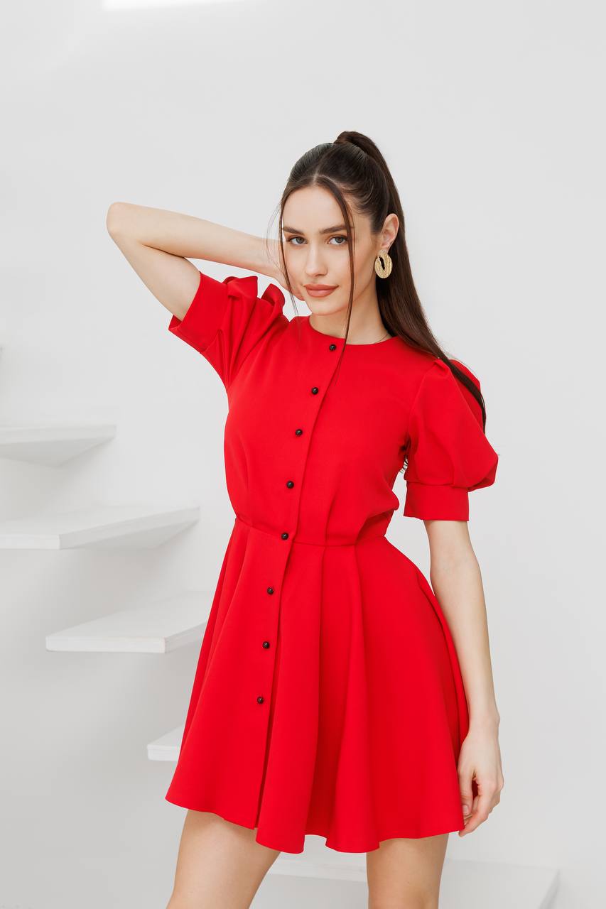 Woman wearing a red dress with black buttons on a white background