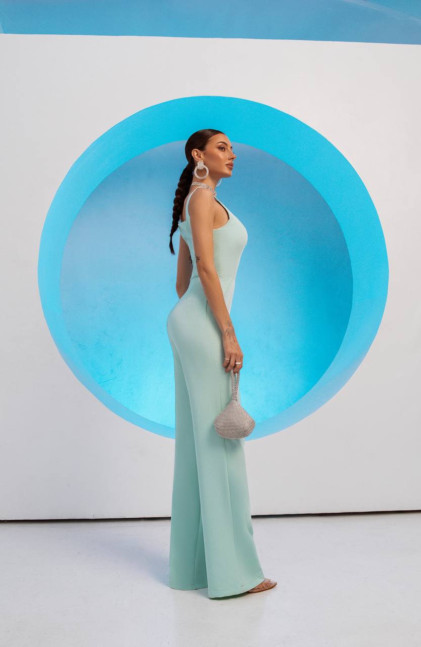 Woman in a light blue evening gown standing in front of a large circular blue light.