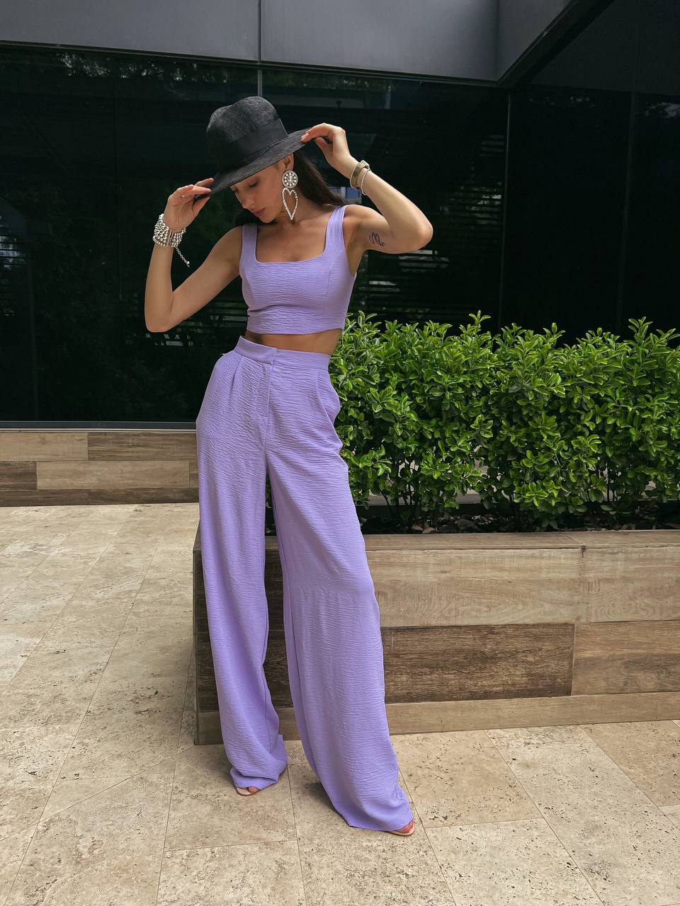 Person wearing a purple outfit with a black hat in an outdoor setting.