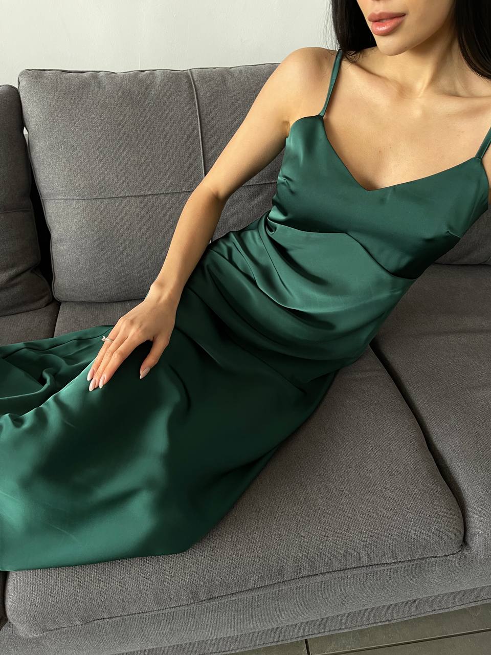 Woman wearing a green dress sitting on a gray couch.