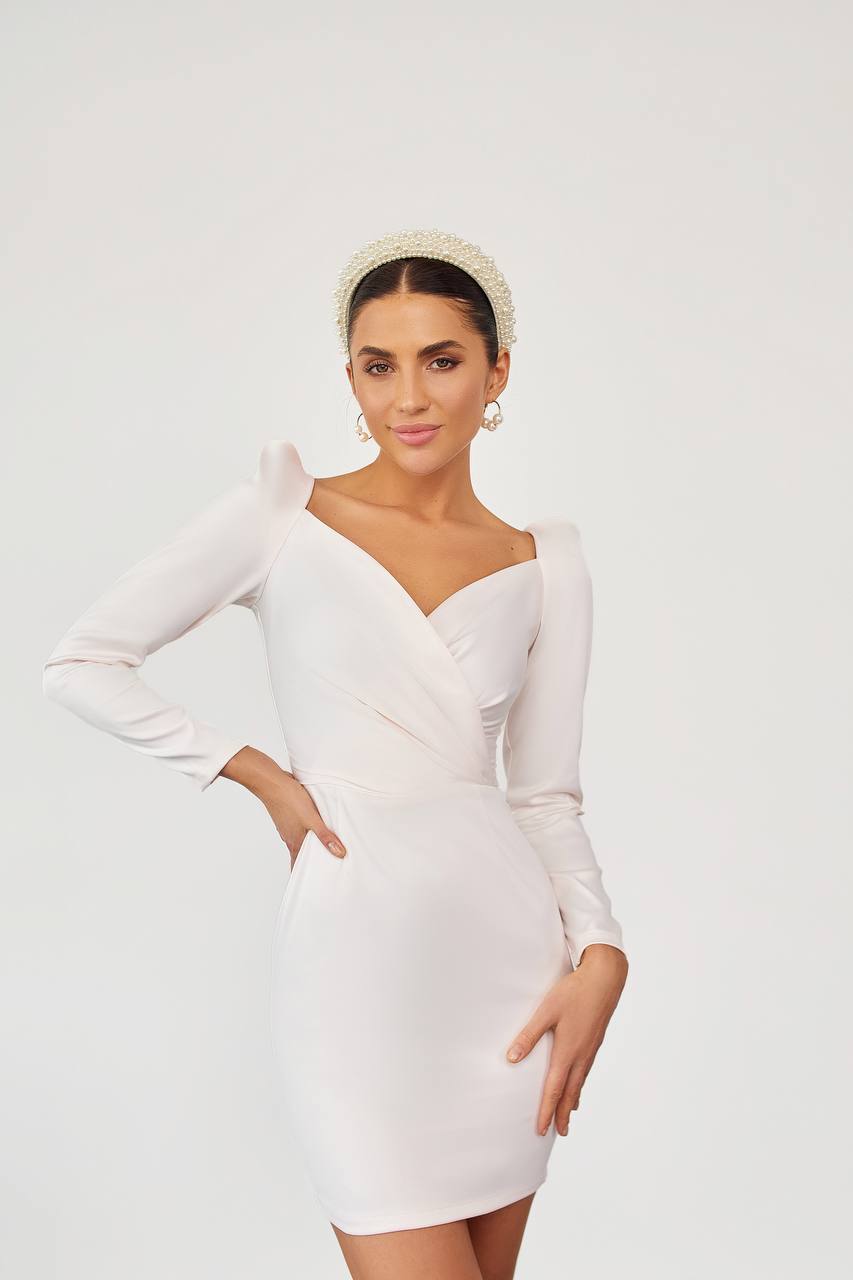 Woman wearing a white dress with long sleeves on a plain background