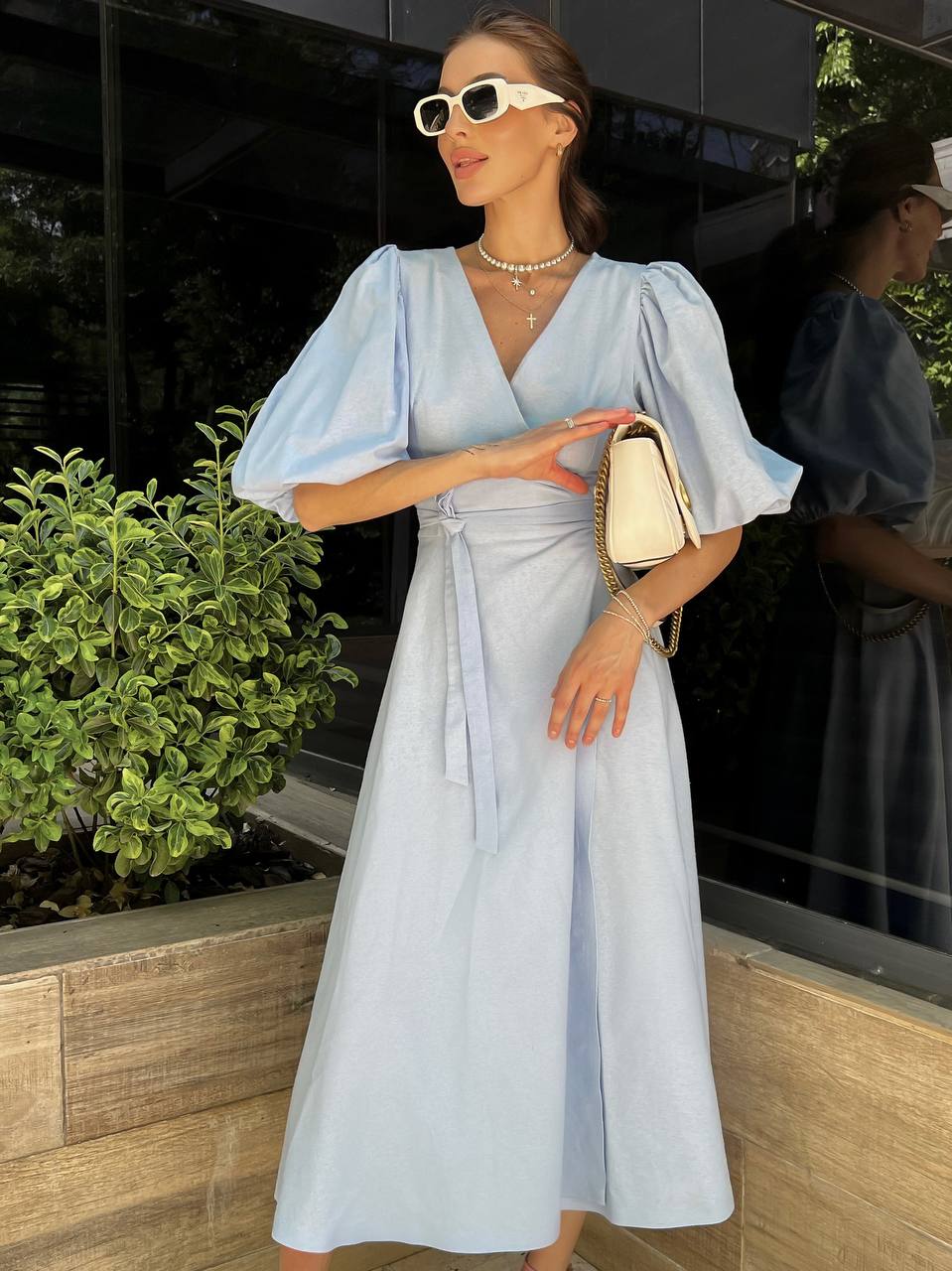 Woman in a light blue dress standing outdoors with a blurred background