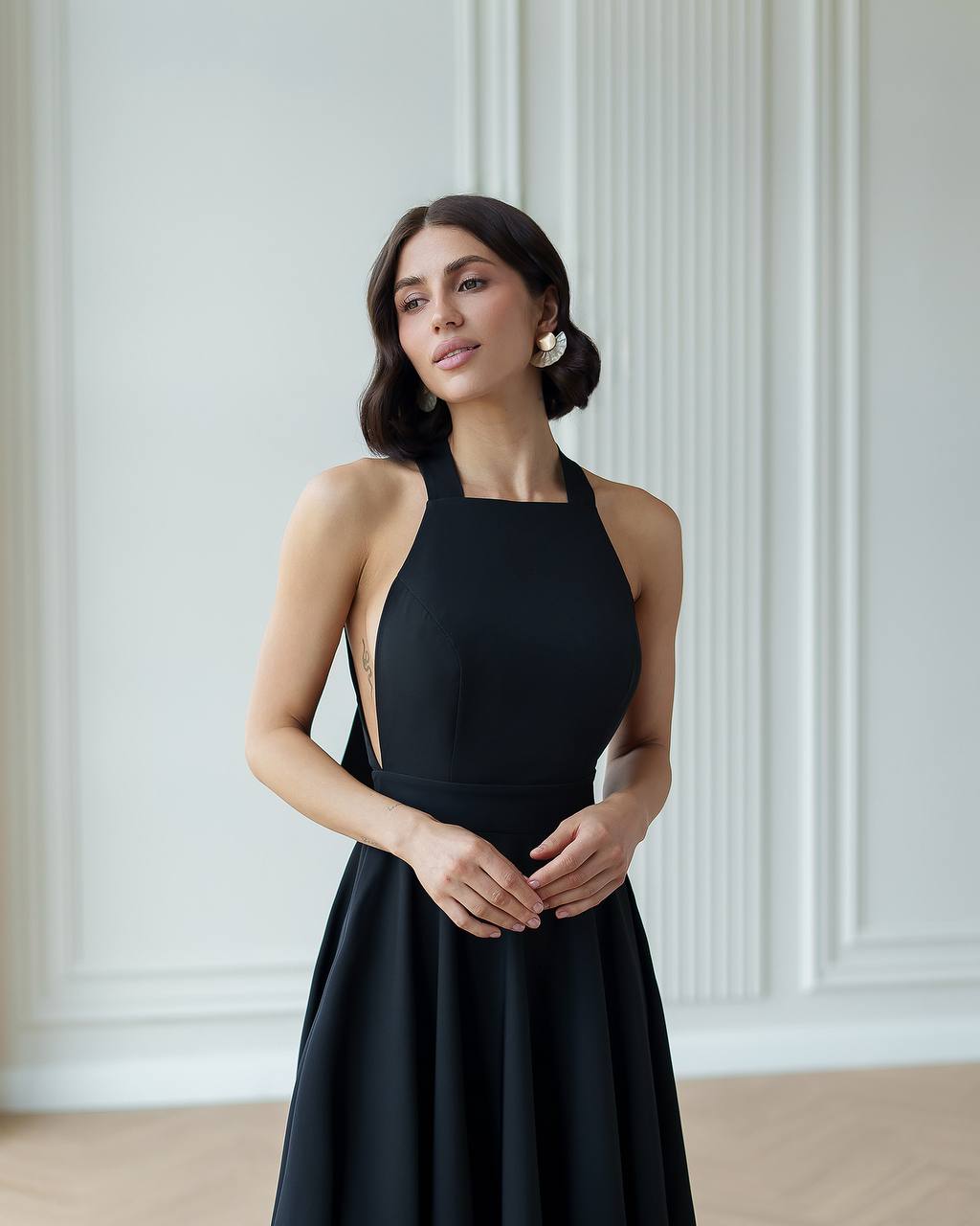 Woman wearing a black dress against a white wall