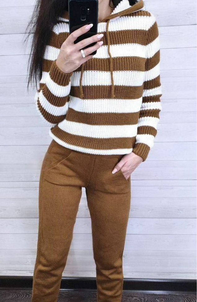 Person wearing a brown and white striped sweater with brown pants against a light gray background