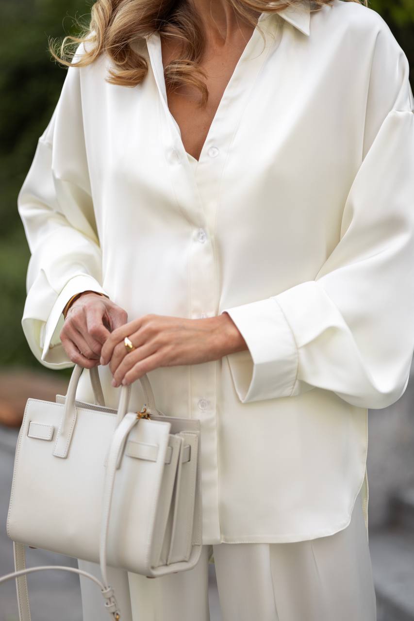 Person wearing a white outfit holding a matching handbag.