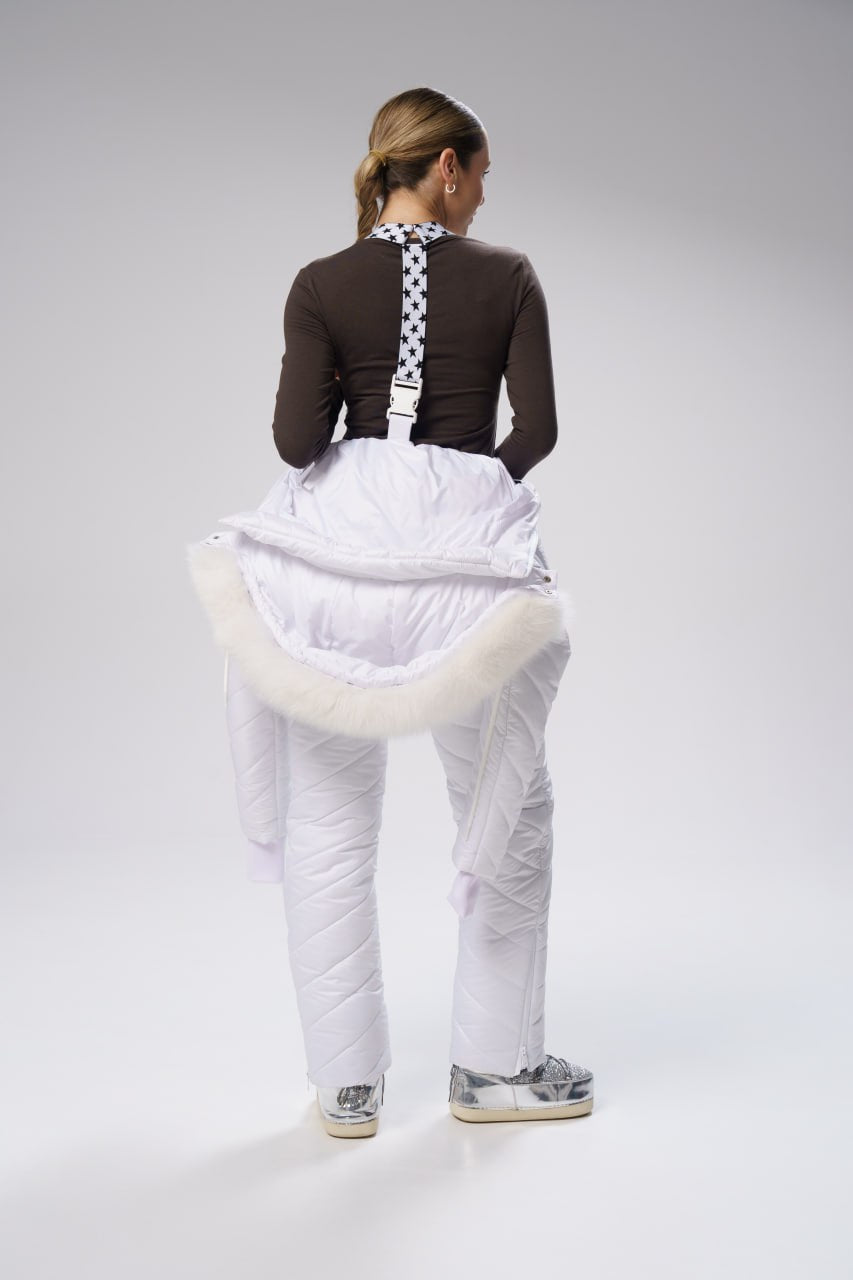 Person wearing a brown top with a checkered pattern, white puffy pants, and sneakers on a gray background