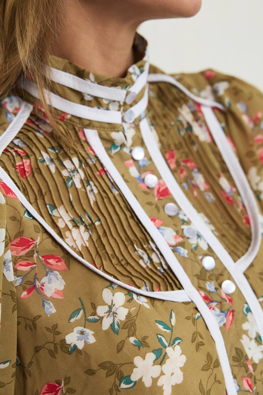 Close-up of a person wearing a floral dress with white straps.