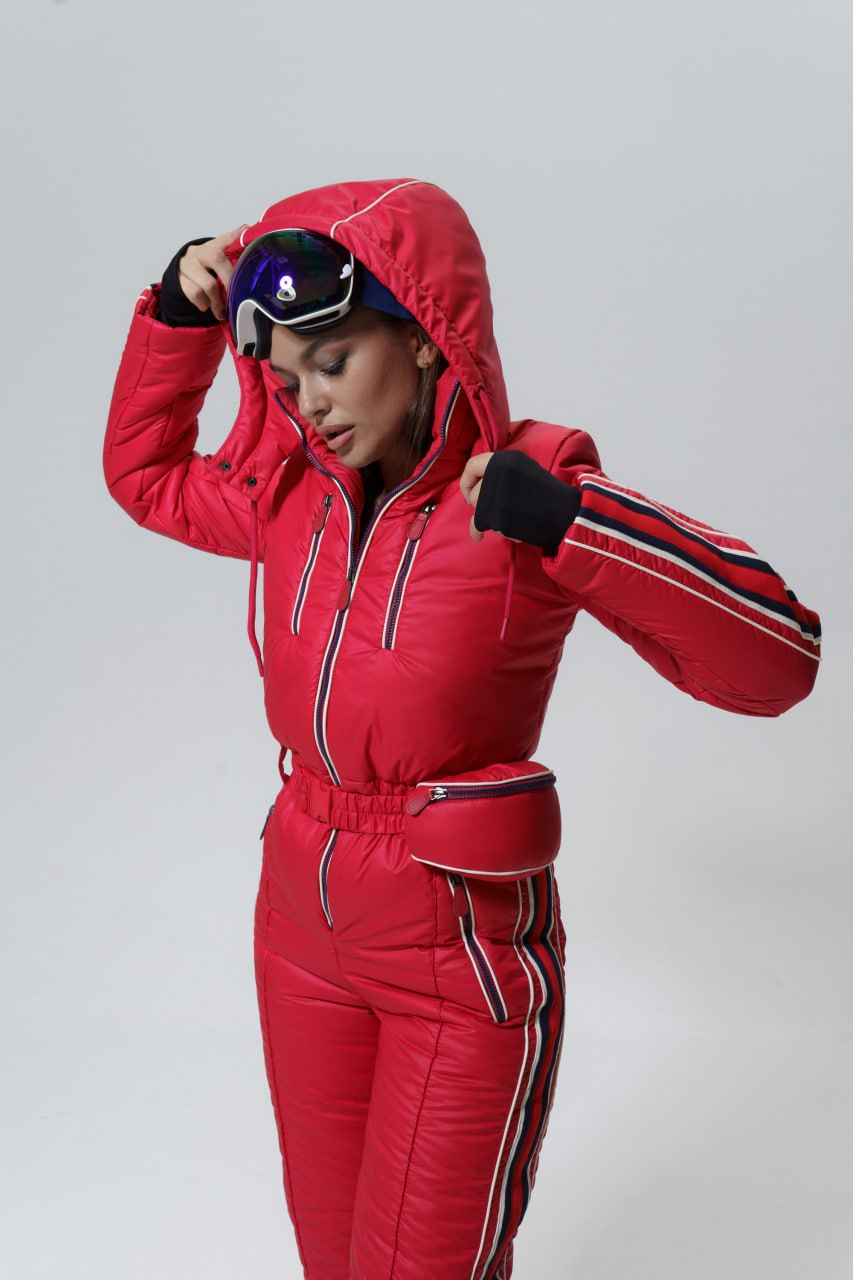 Person wearing a red ski suit with a hood on a gray background