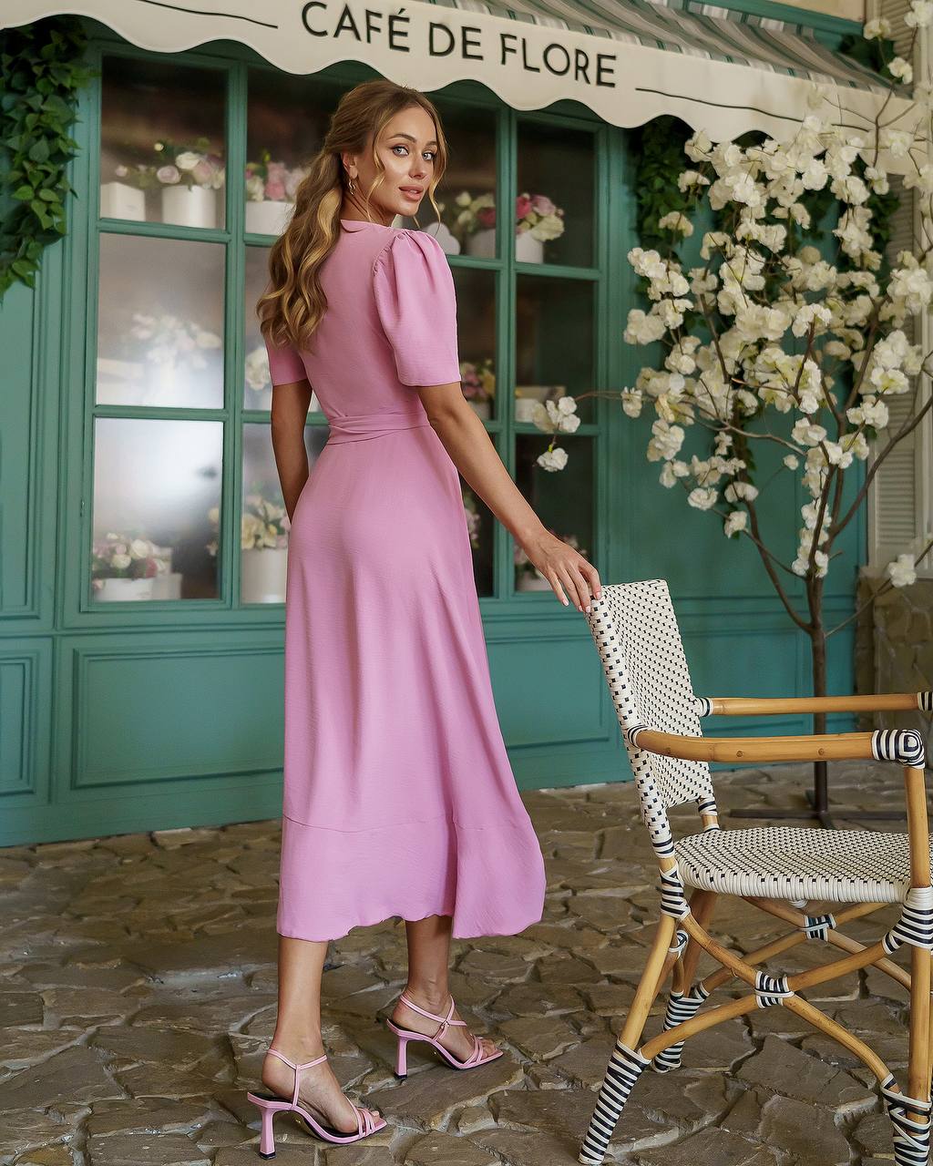 Woman in a pink dress standing in front of a café named 'Café de Flore'.