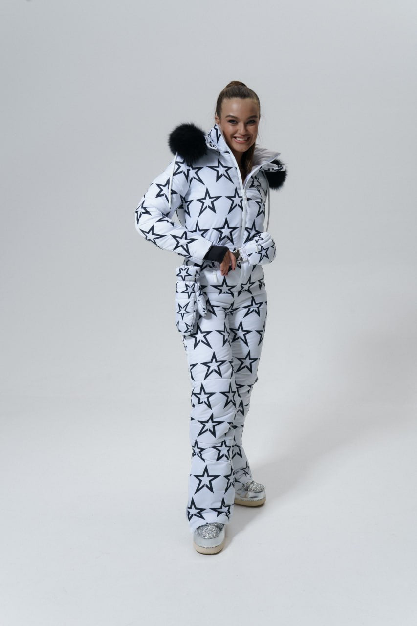 Person wearing a white onesie with black star patterns on a plain background