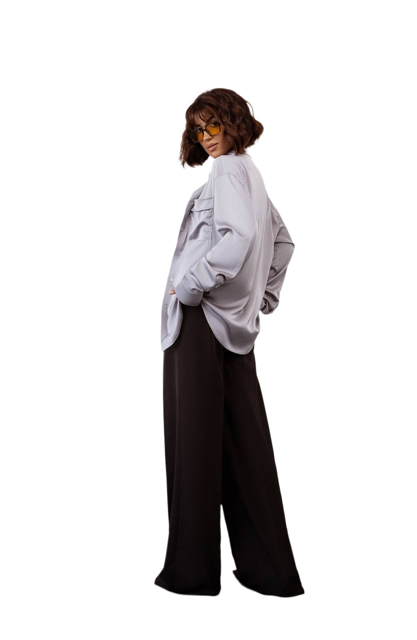 Person wearing a light gray oversized shirt and black pants on a white background