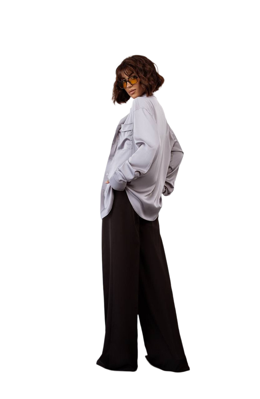 Person wearing a light gray oversized shirt and black pants on a white background