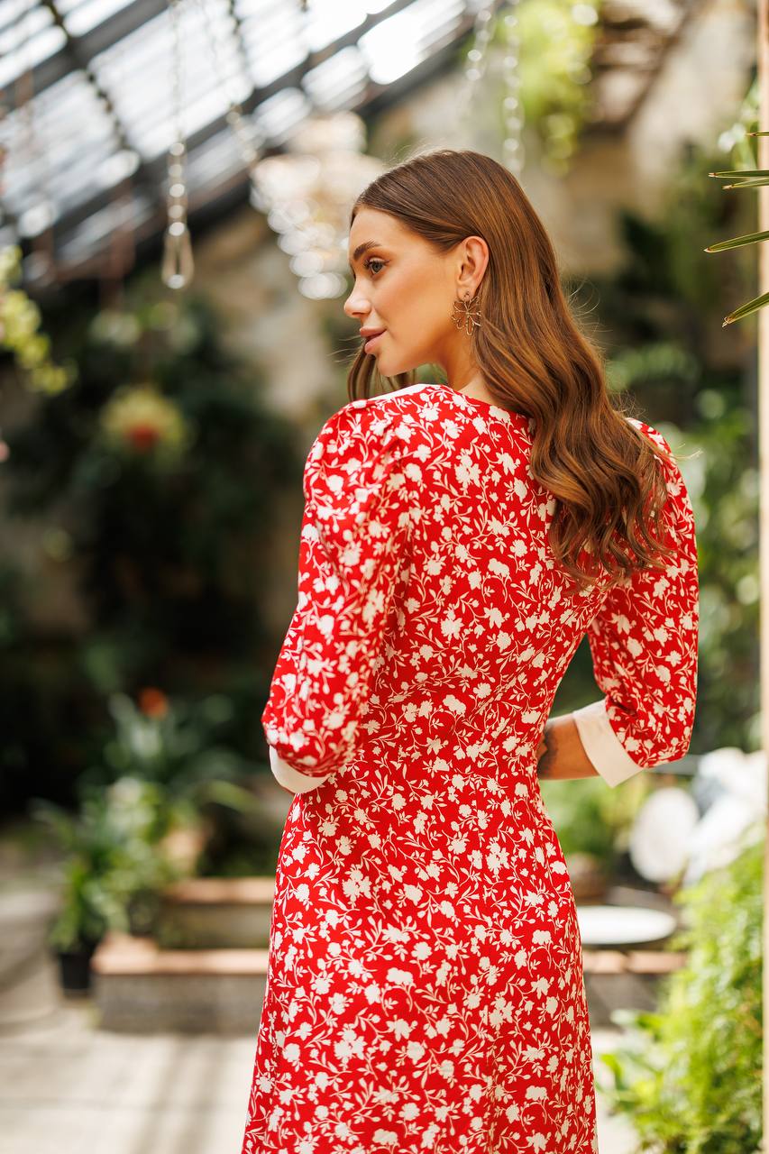 Woman in a red floral dress standing in a greenhouse