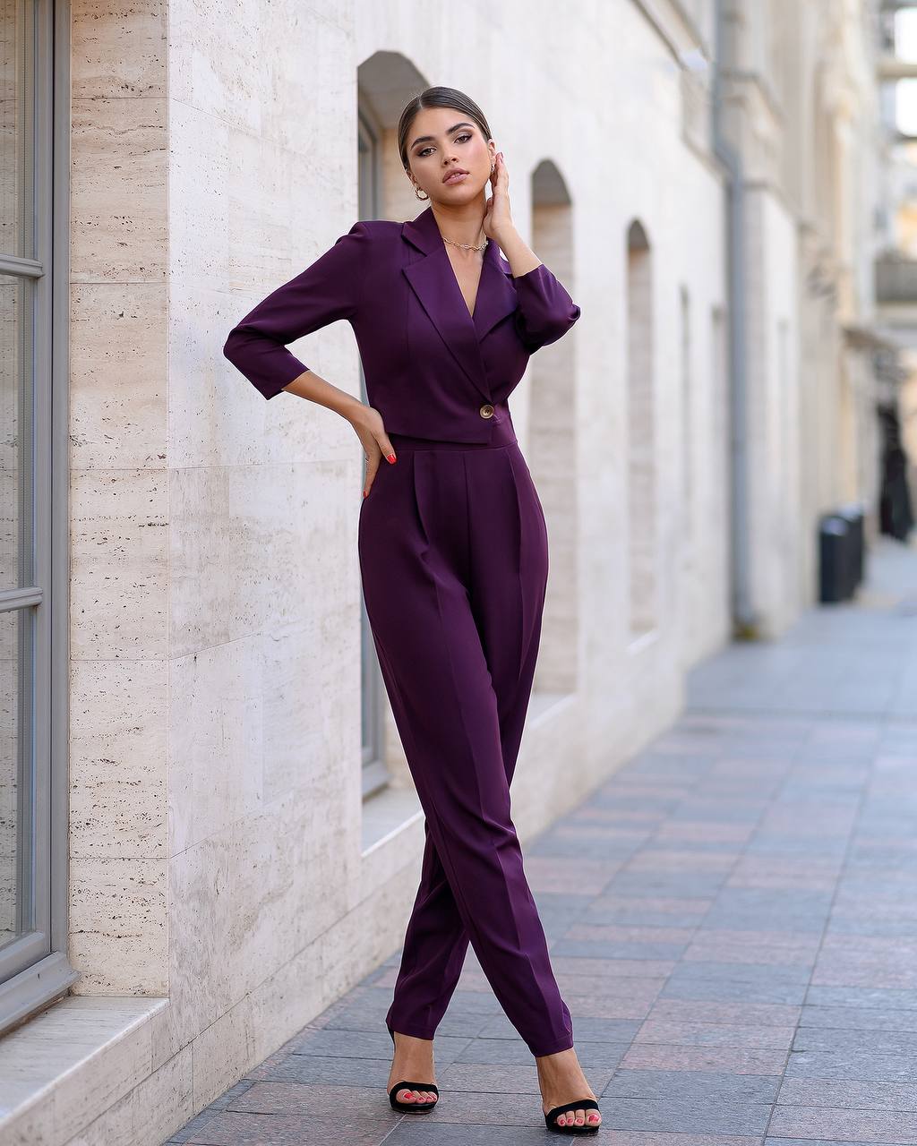 Woman in a purple outfit standing on a city street.