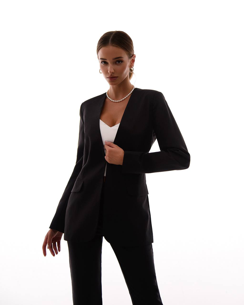 Woman wearing a black suit with a white top on a white background