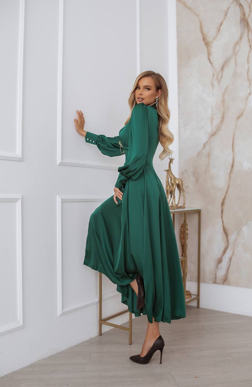 Woman in a green dress posing in a stylish interior setting