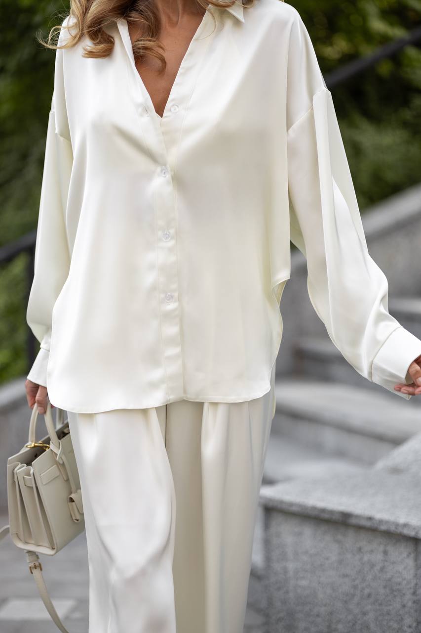 Person wearing a white blouse and pants with a handbag, standing on steps outdoors.