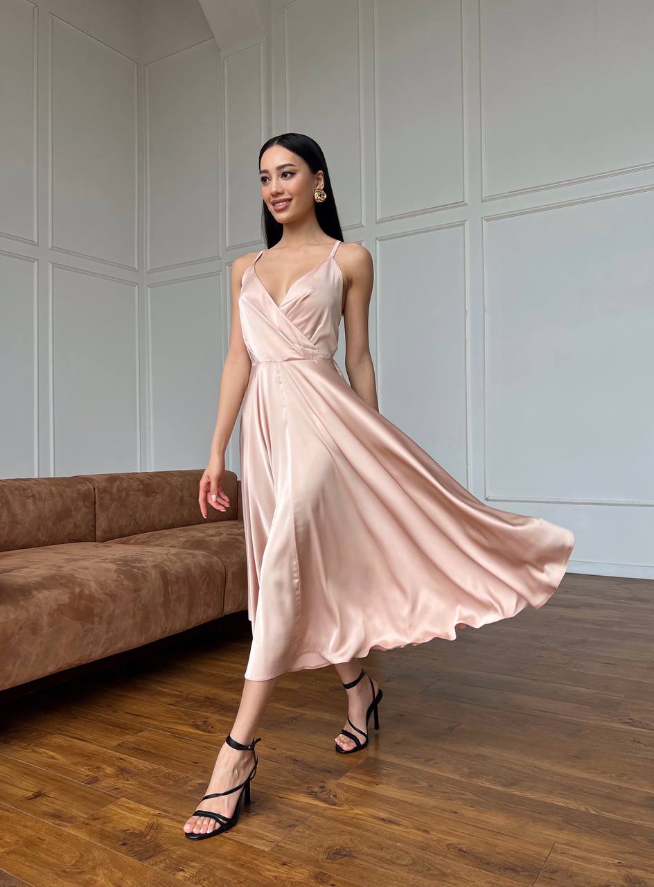 Woman in a pink dress standing in a room with wooden flooring and a sofa.