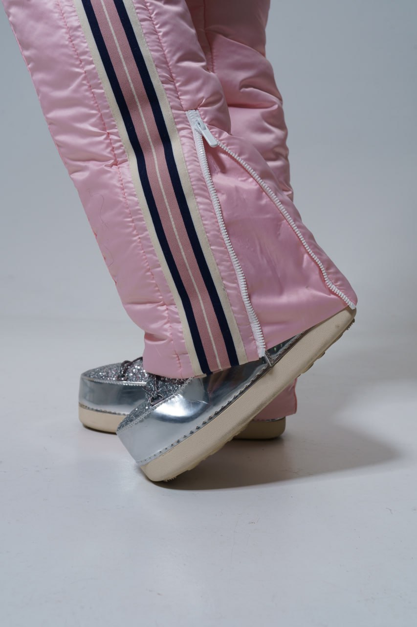 Pink pants with white and navy stripes worn by a person, paired with silver shoes on a light gray background.