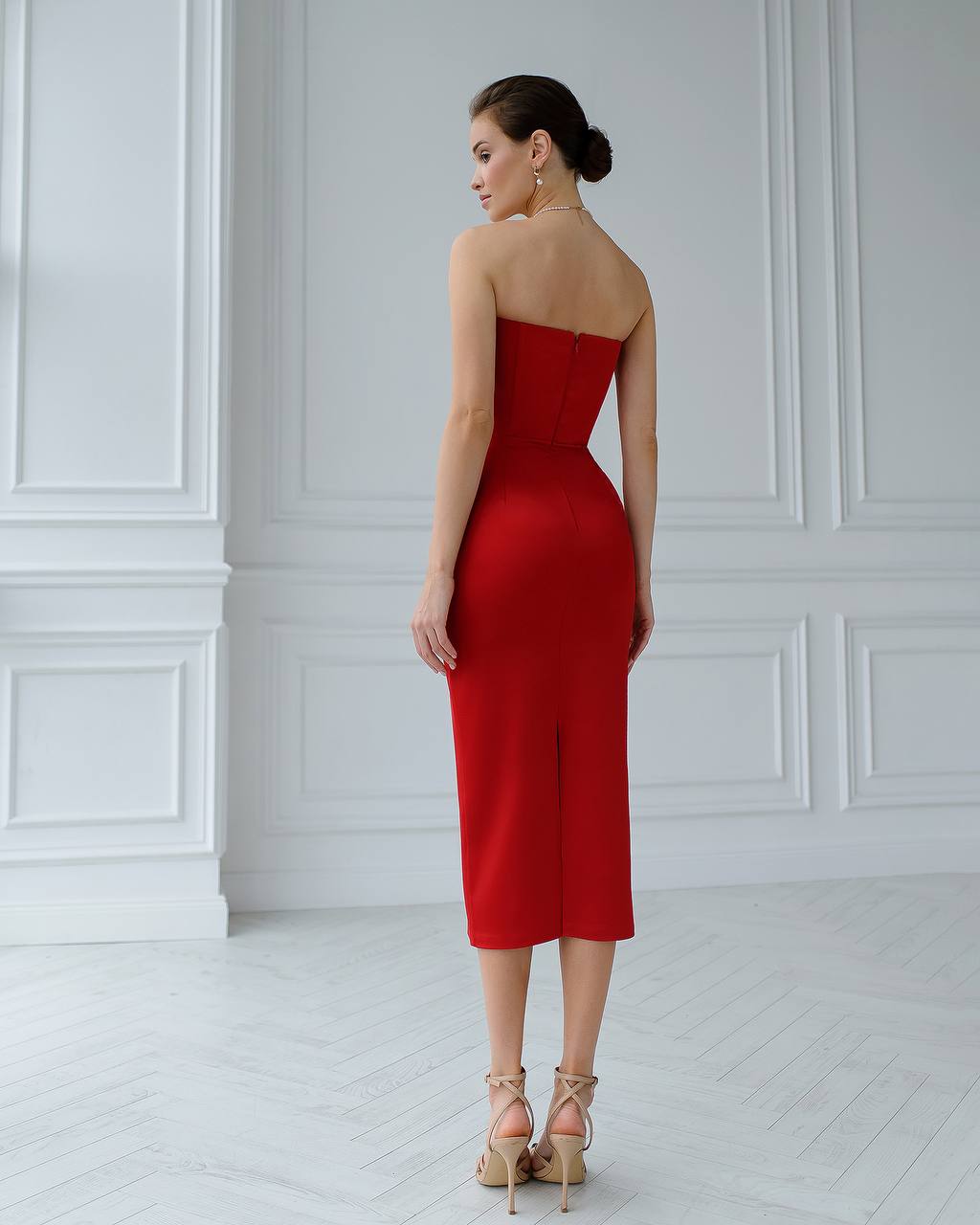 Woman wearing a red strapless dress in a white room