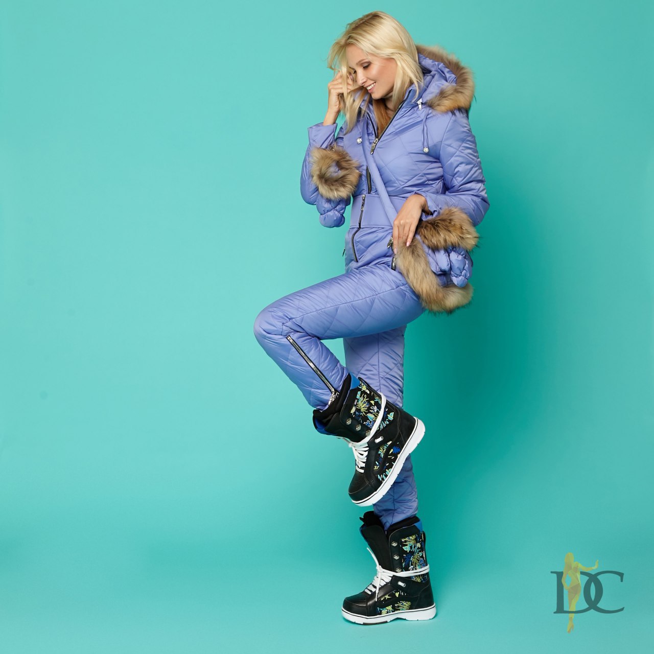 Person wearing a purple snowsuit with fur trim on a teal background