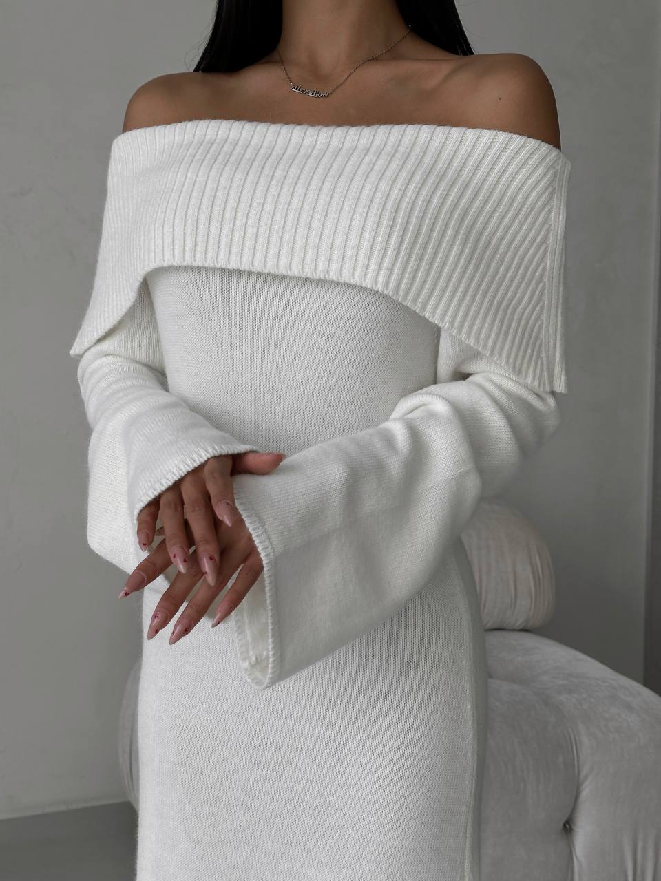 White off-shoulder sweater worn by a person against a neutral background