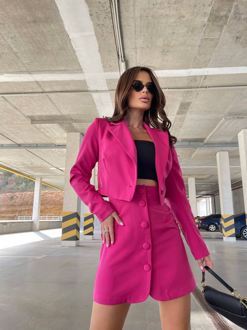 Woman in a bright pink outfit standing in an indoor parking garage.