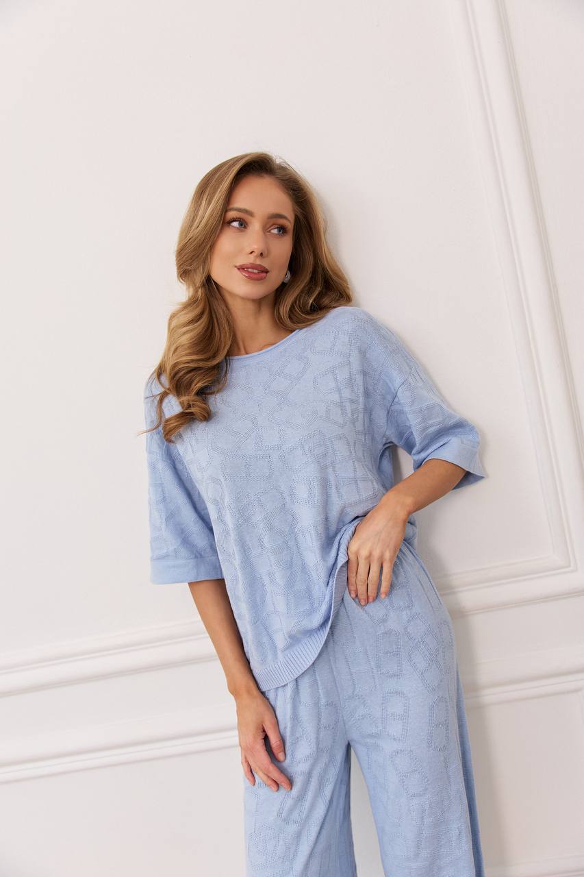 Woman wearing a light blue outfit against a white wall