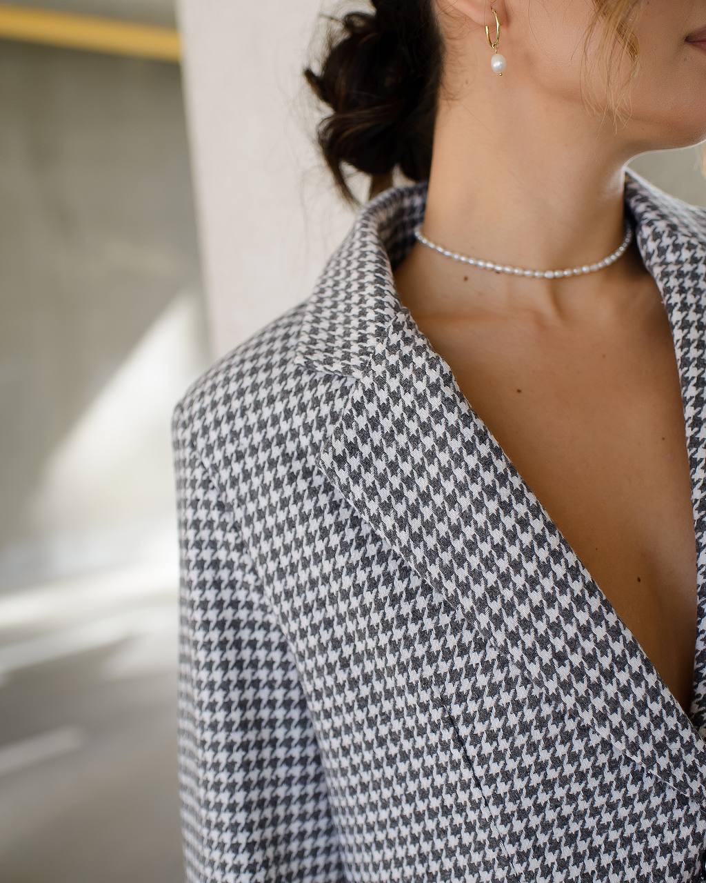 Person wearing a houndstooth patterned blazer with a blurred background