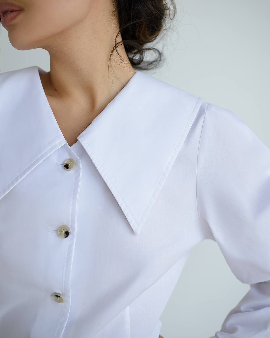 Close-up of a white shirt with buttons on a plain background