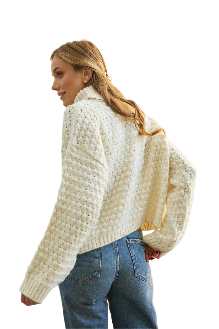 Woman wearing a cream knitted cardigan and blue jeans on a white background