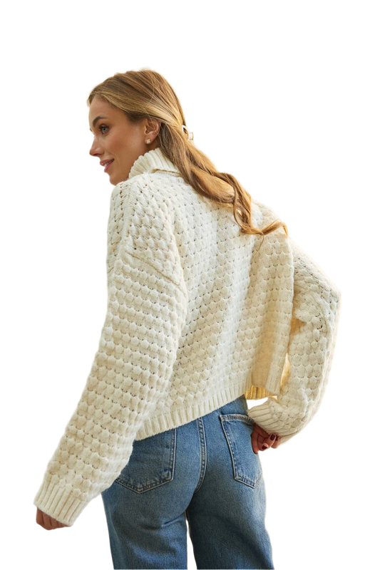 Woman wearing a cream knitted cardigan and blue jeans on a white background