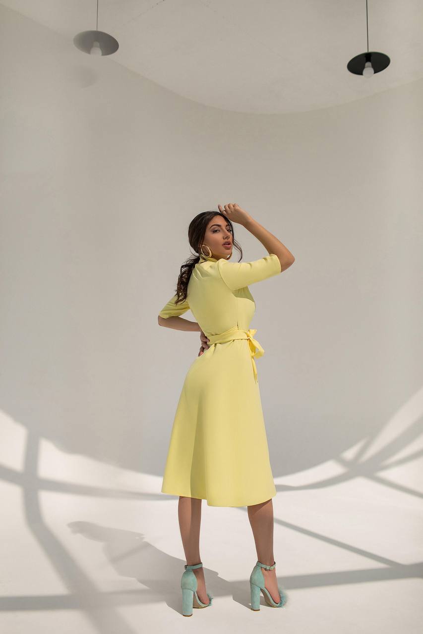 Woman wearing a yellow dress with a belt in a minimalistic setting