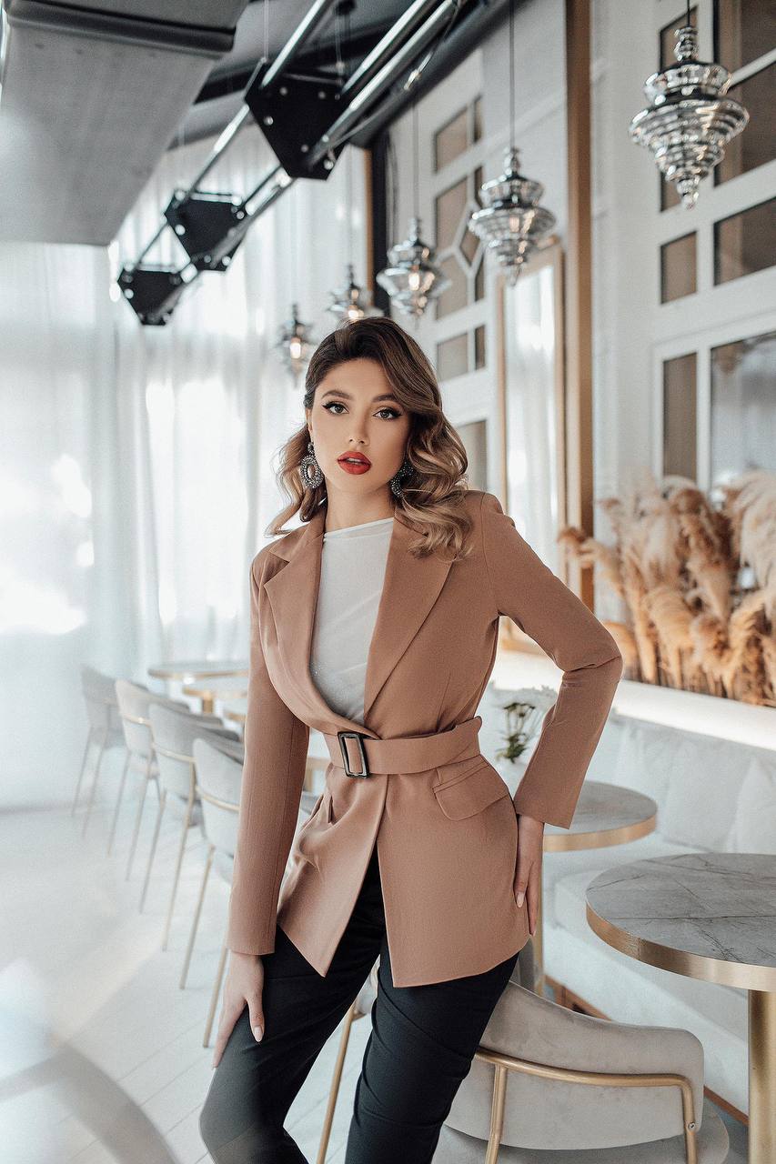 Woman in a beige coat standing in a modern cafe.