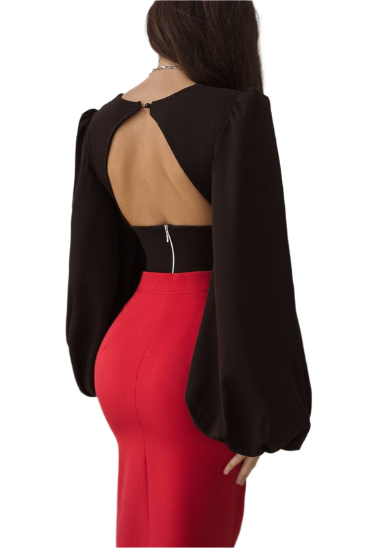 Person wearing a black open-back top and red pants on a white background