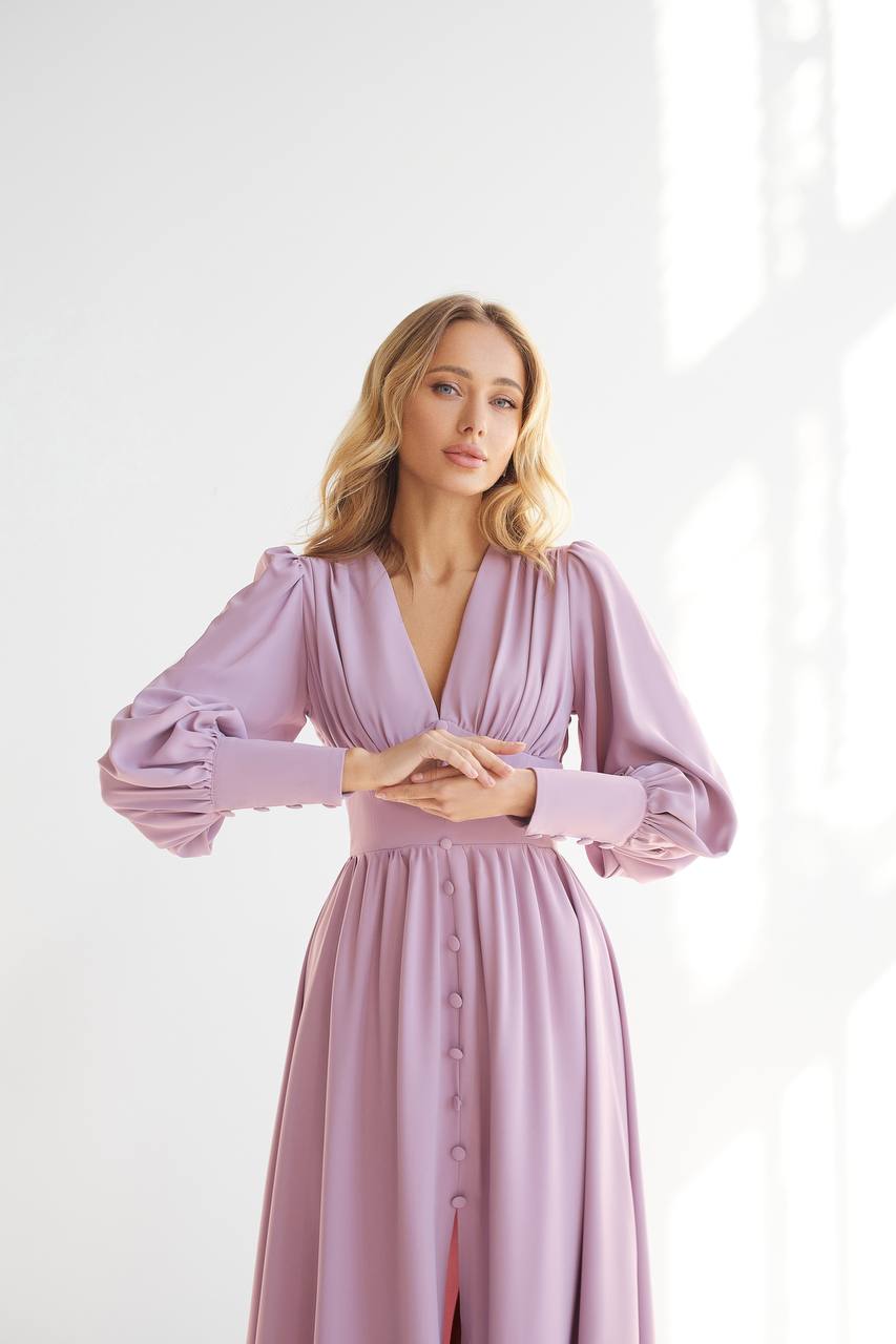 Woman wearing a lavender dress with long sleeves against a white background
