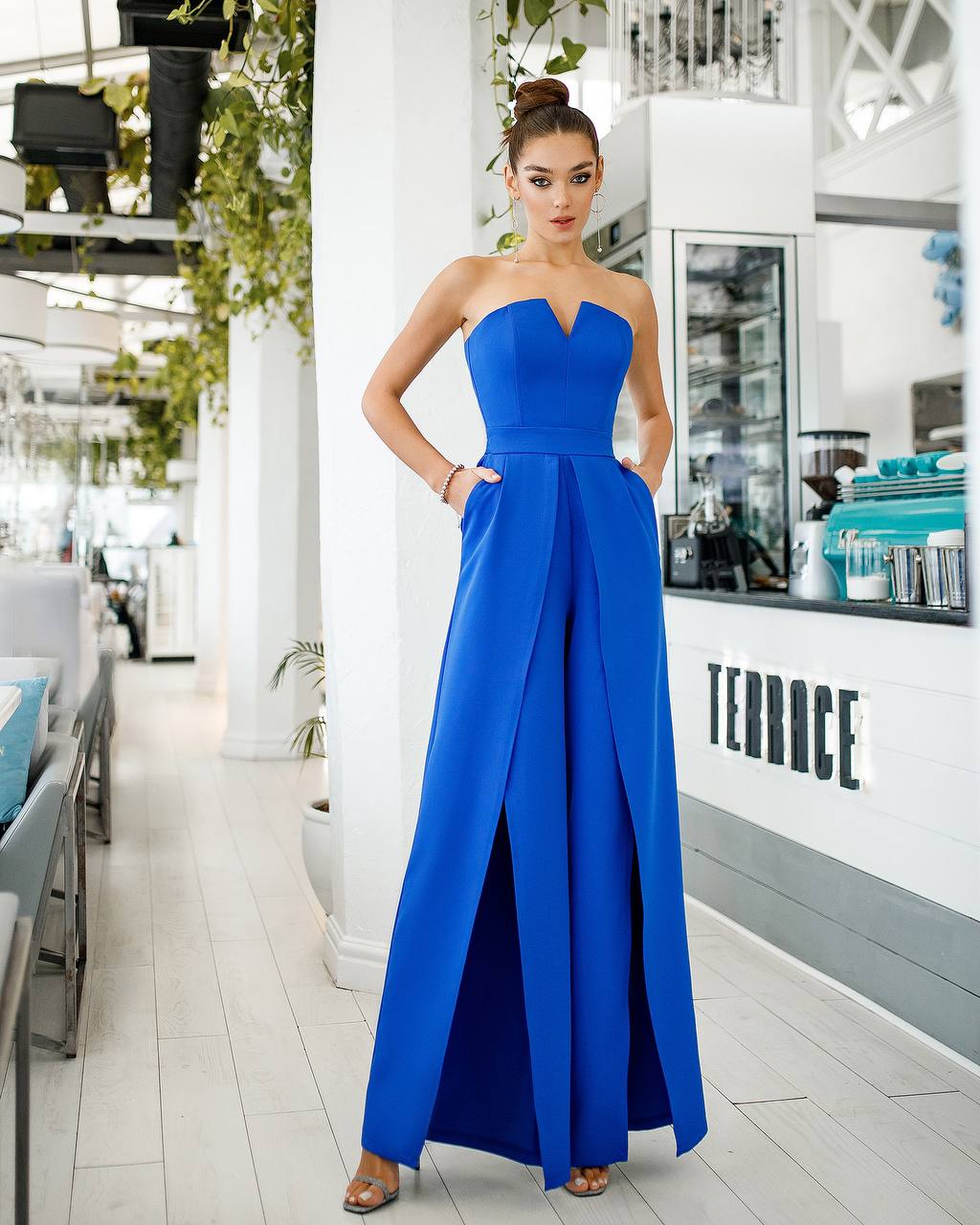 Woman in a blue strapless gown standing in a modern indoor setting with 'Terrace' branding.