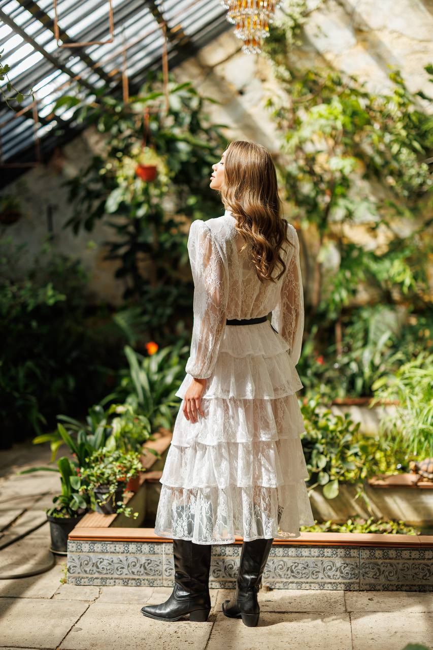 Woman in a white dress standing in a greenhouse filled with plants