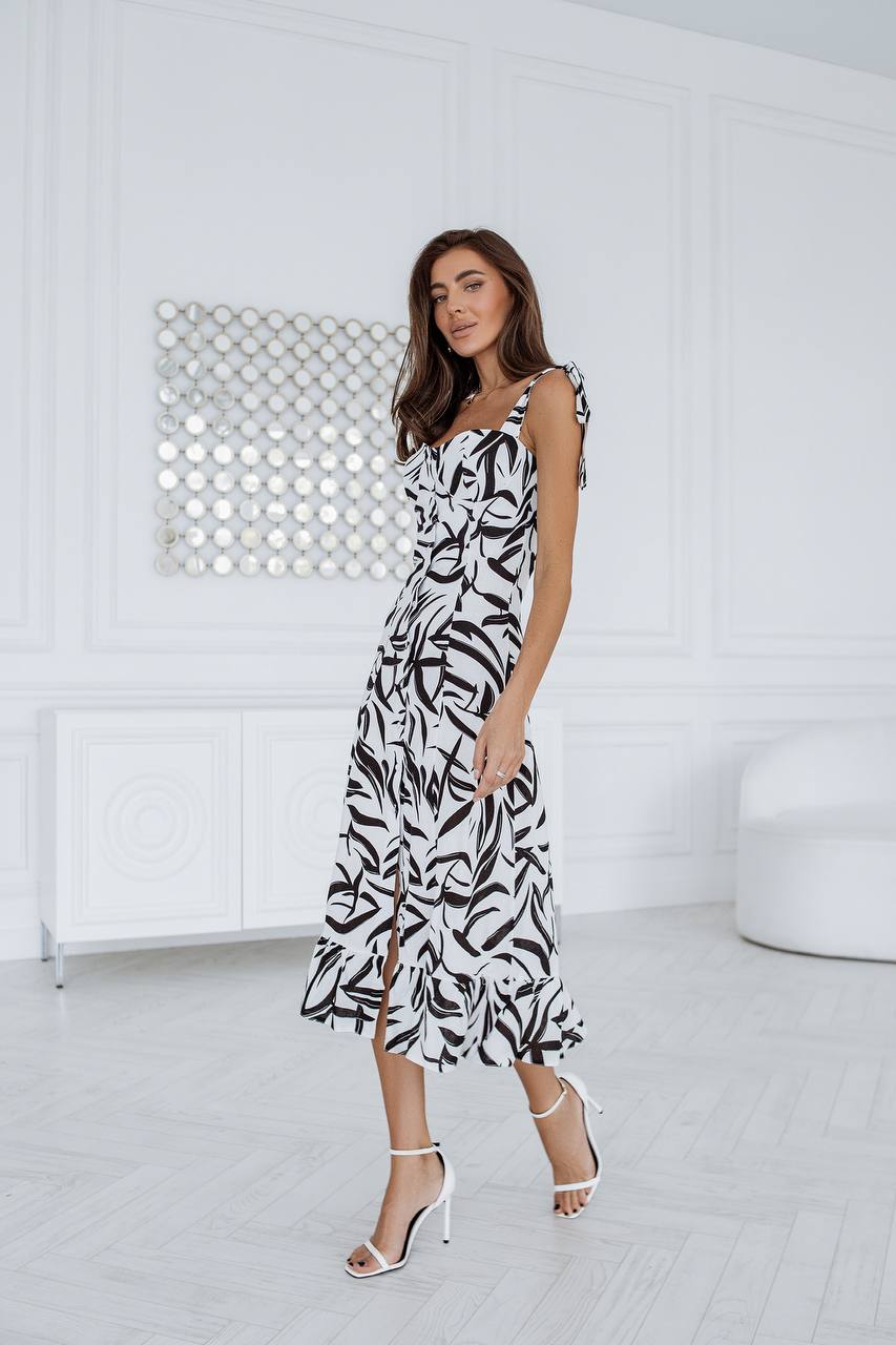 Woman wearing a black and white patterned dress in a minimalistic room.