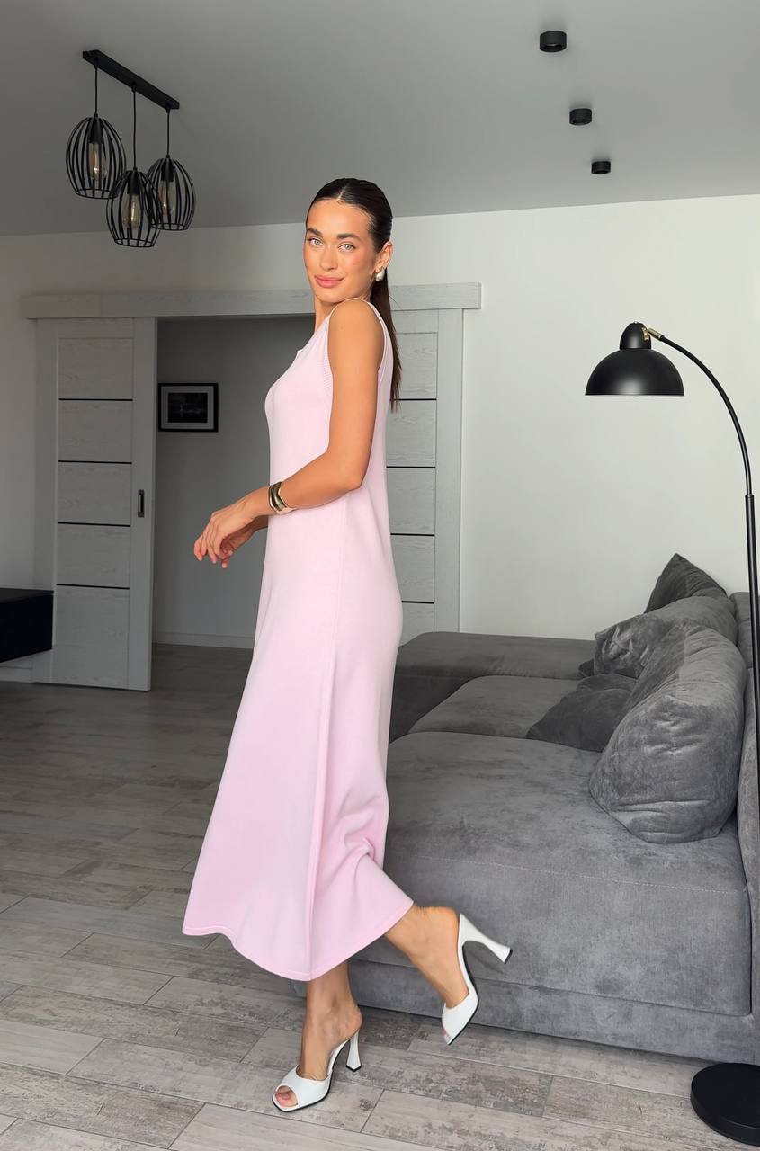 Woman in a pink dress standing in a modern living room.