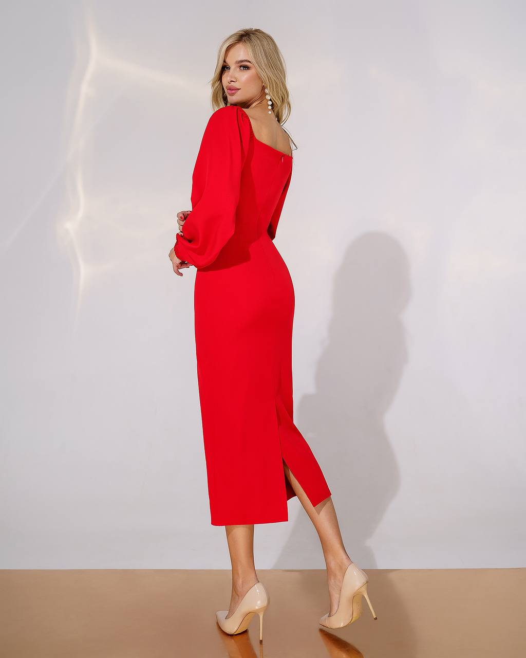 Woman wearing a red dress with a slit on a plain background