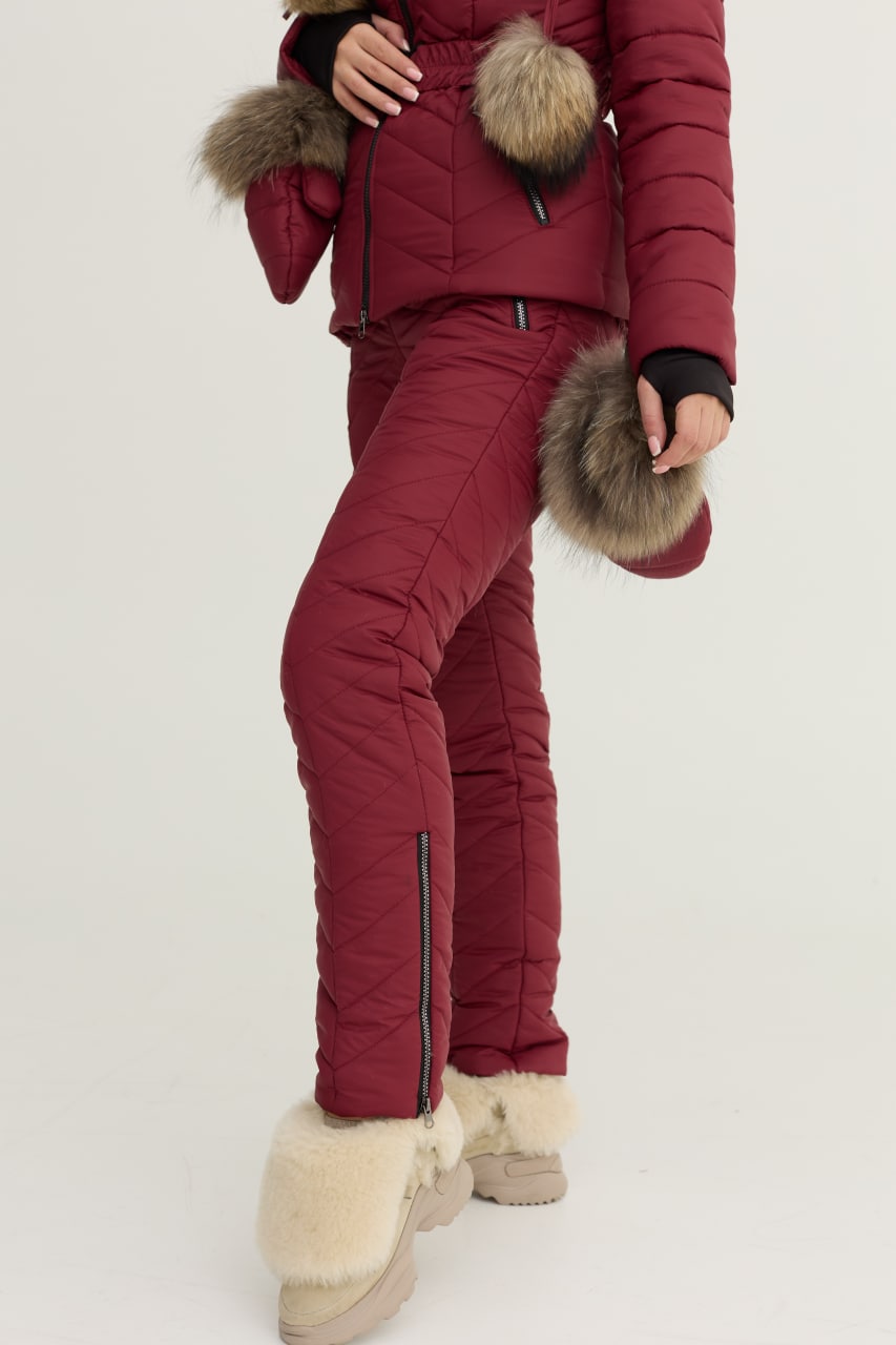 Person wearing a red winter outfit with fur-lined hood and cuffs on a white background